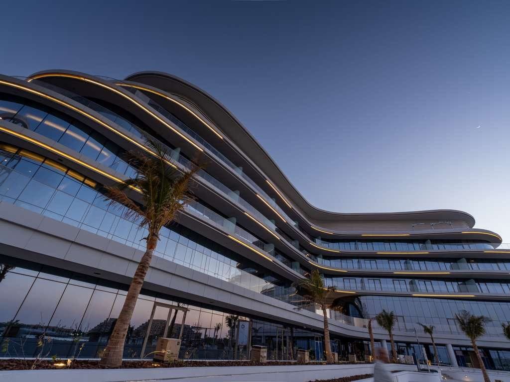 SO Hotel, Ras Al Khaimah — curved waterfront façade at dusk.